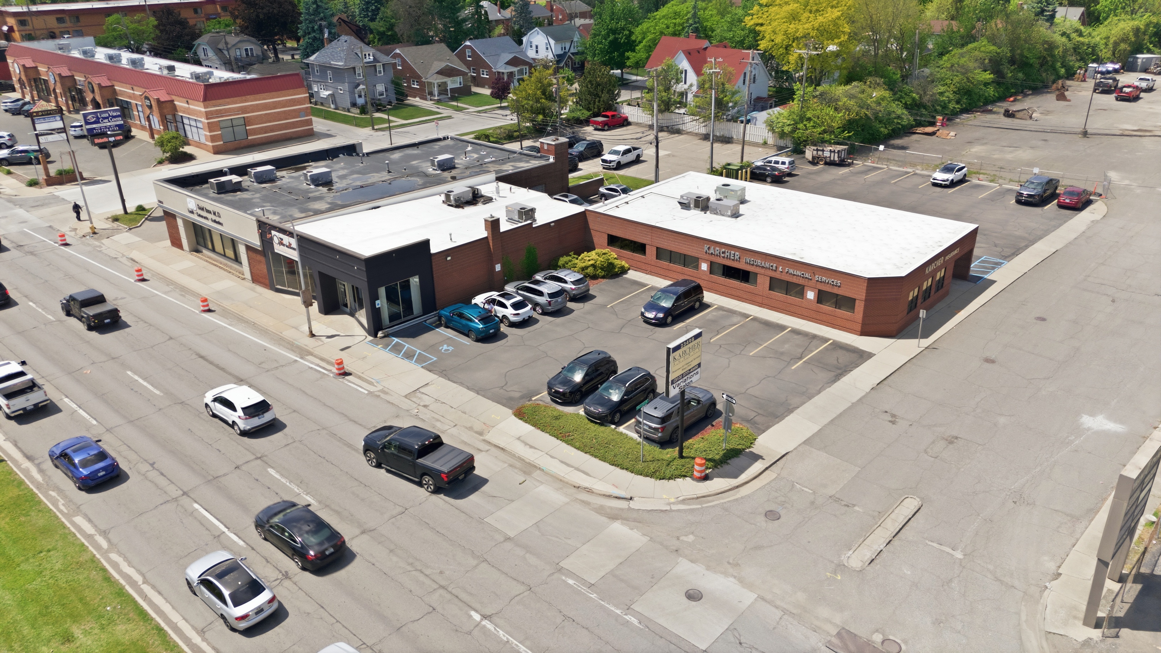 Aerial drone photograph of a commercial building and its parking lot on a busy Metro Detroit road