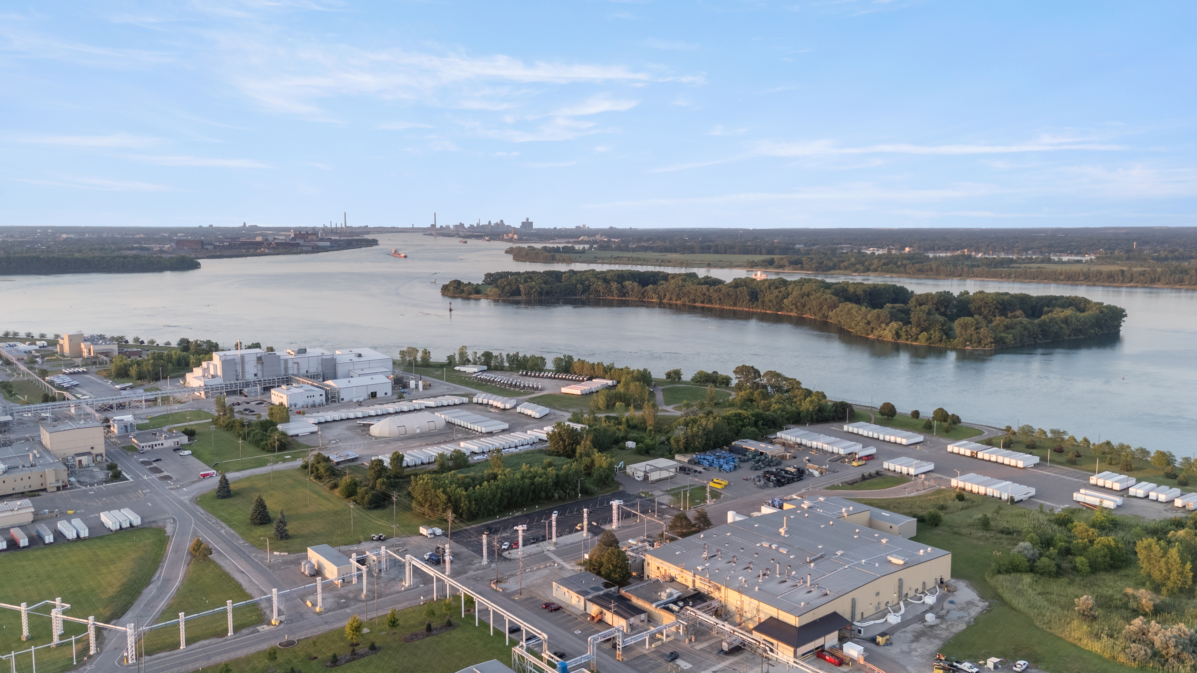 Aerial drone photograph of an industrial property on the river, with islands and the city skyline in the distance