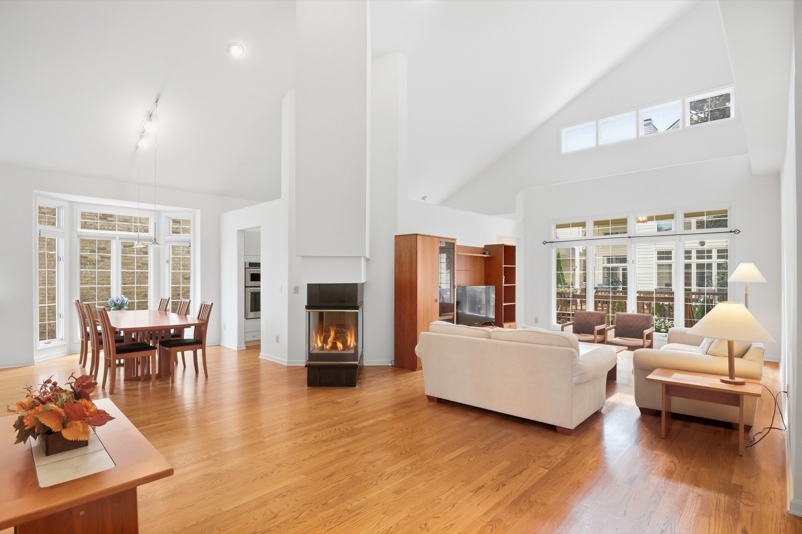 HDR interior photograph of a vaulted living and dining room with the fireplace lit