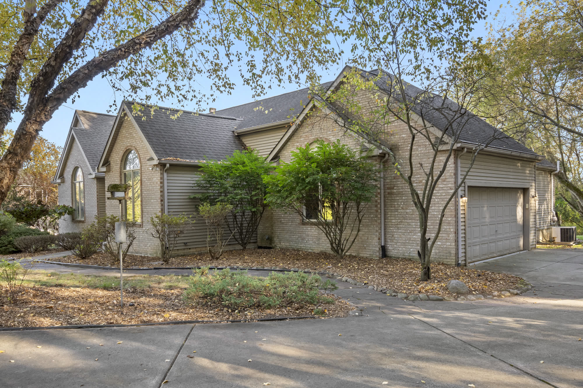 Brick ranch home photographed in fall 2025, with bare branches and fallen leaves