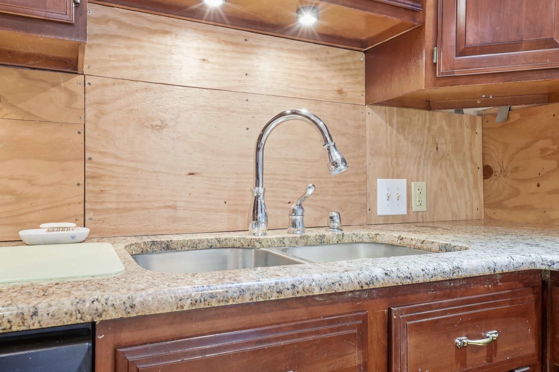 Close-focus photograph of a kitchen faucet and stone counter