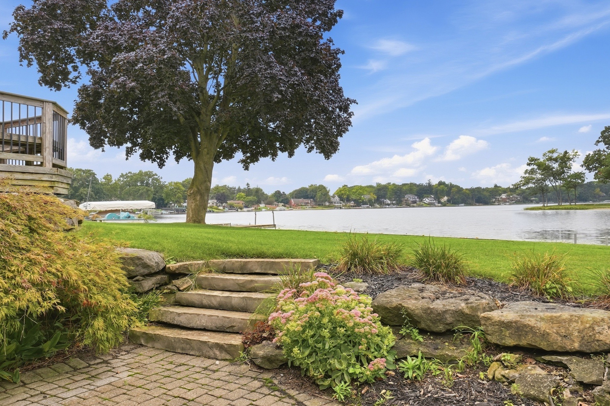 The same waterfront exterior after sky replacement, with a blue sky and cloud detail