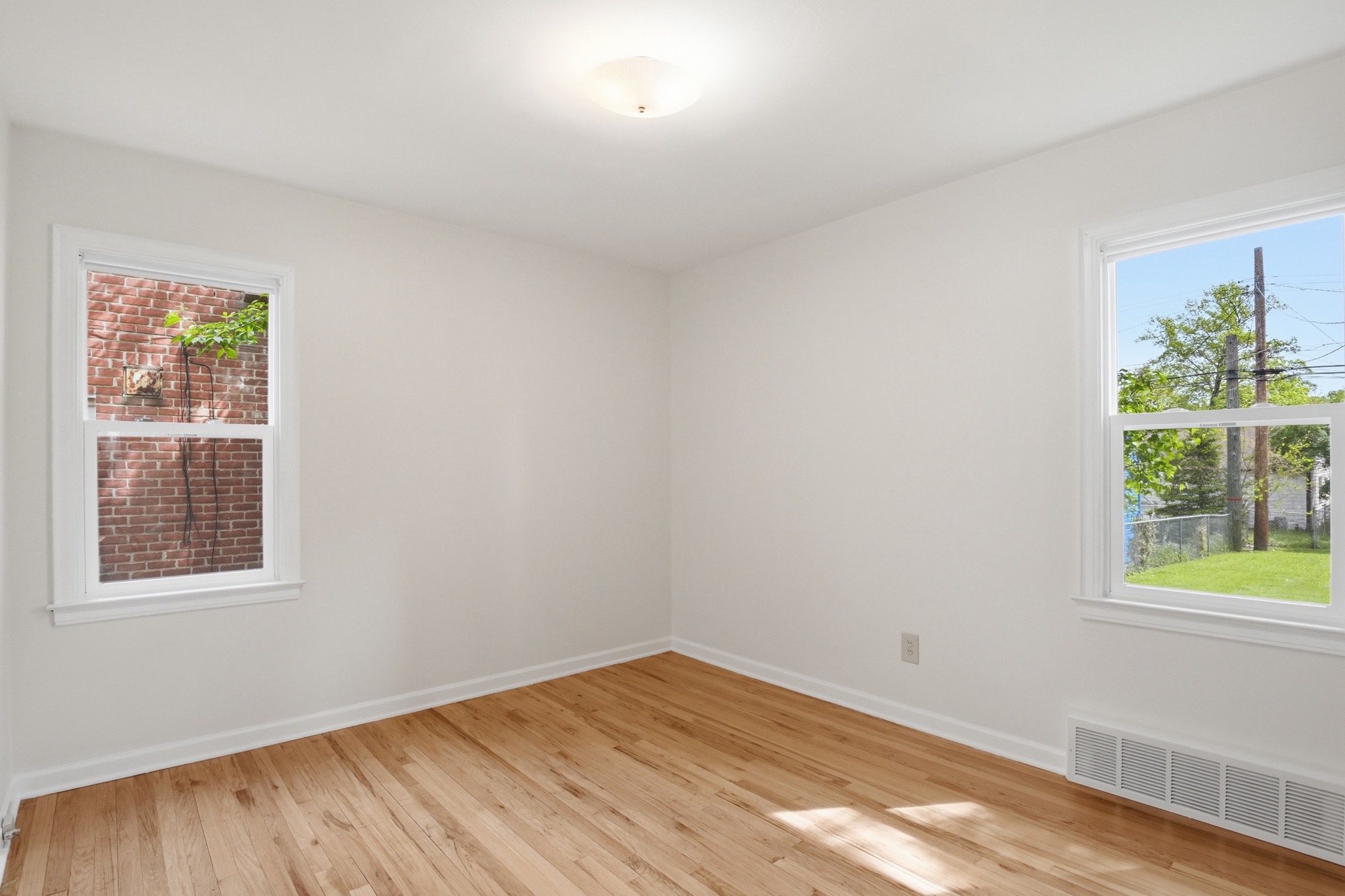 Empty bedroom with hardwood floors and two windows