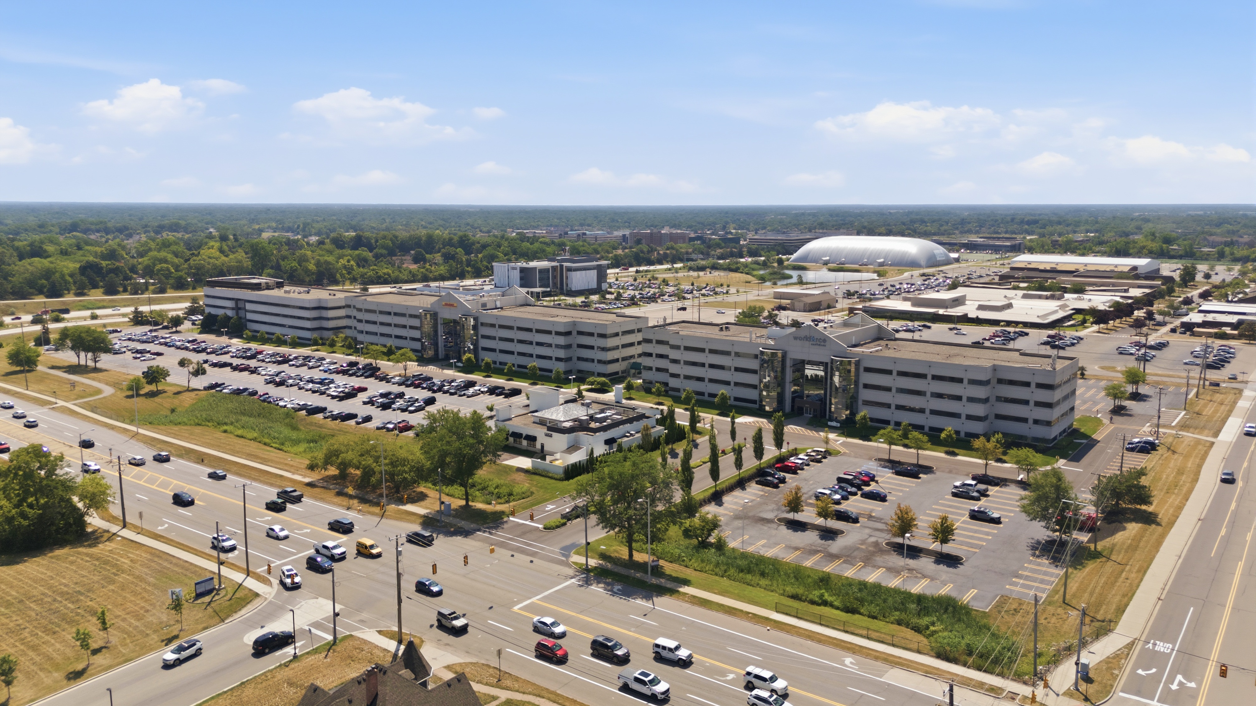 Aerial photograph of a commercial building and its parking lot on a busy Metro Detroit road
